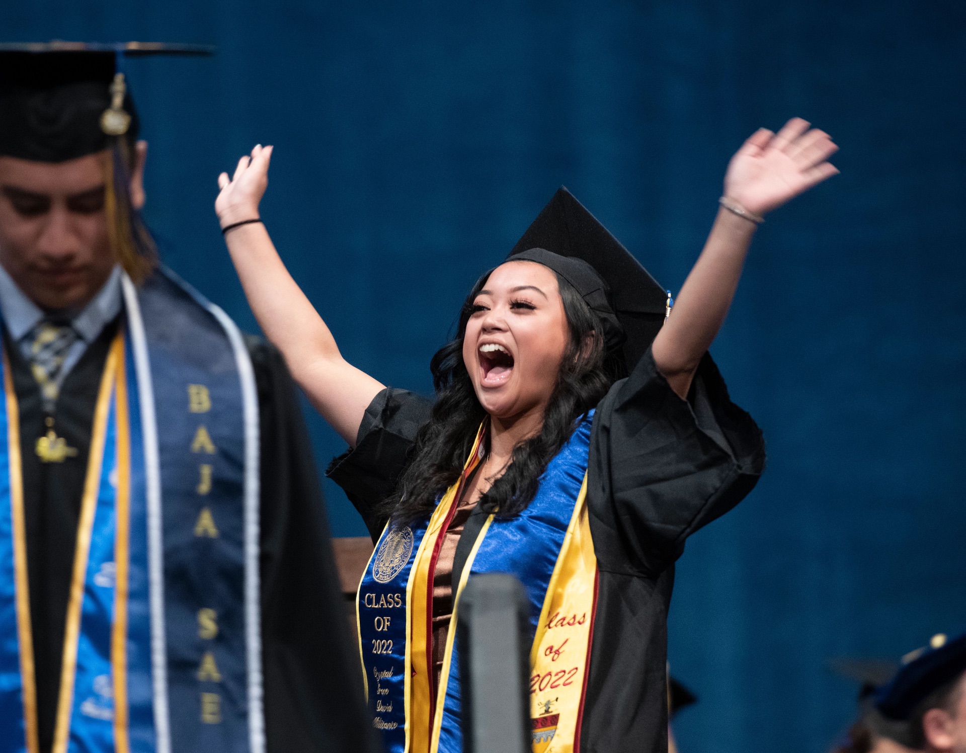Commencement: a recent graduate with her hands raised in celebration